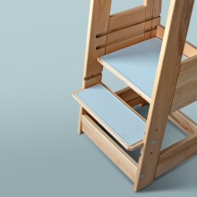 Wooden step stool with light blue cushioned steps on a soft gray background.