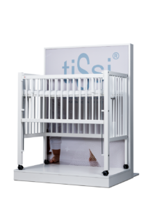 White crib with wheels in front of a large panel displaying 'tiSsi' logo.
