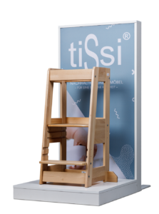 Wooden children's chair in front of a blue sign with white text.