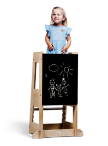 Child standing beside blackboard drawing of three stick figures under a sun.