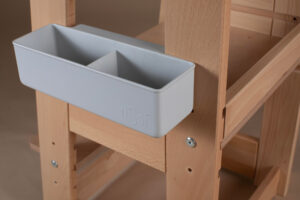 Wooden high chair with a gray plastic storage bin attached on the side.
