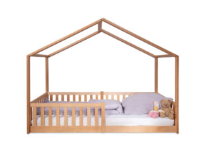 Wooden house-shaped toddler bed with purple bedding and stuffed toys.